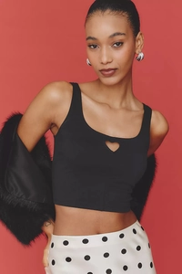 Detailed view of black cropped tank top featuring heart-shaped cutout on red background