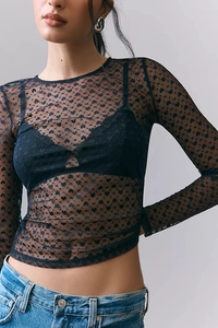 Detailed close-up of sheer black mesh top featuring velvet flocking heart patterns