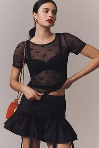 Détail du haut en maille noire transparente avec motifs nœuds et jupe à volants