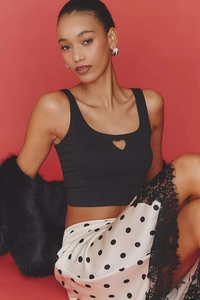 Detail of black slim fit tank top with heart cutout and lace hem polka dot skirt