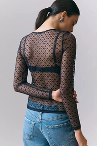 Detail view of black sheer mesh top featuring velvet heart patterns and fine edging