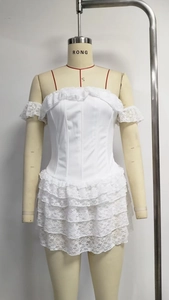 Detail of white lace tiered dress featuring ruffled corset bodice and red straps