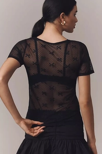 Détails du dos d'un haut en tulle transparent avec motifs nœuds noirs et texture à pois