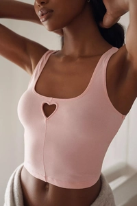 Detail of a pink knit crop top featuring a central heart-shaped cutout and slim fit design