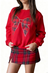 Detail of red crewneck sweatshirt with large green and red tartan bow and gold edges