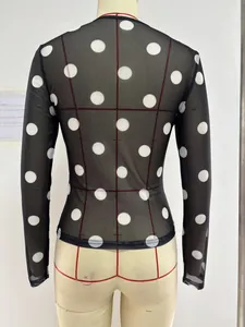Detail of sheer black mesh fabric with white polka dot pattern on a long-sleeve top