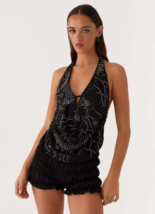 Détail de la broderie florale à paillettes sur un haut licou noir avec décolleté plongeant