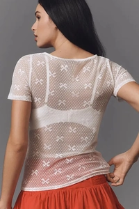 Vue détaillée du haut blanc en mesh transparent avec motifs de nœuds et col rond
