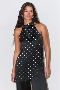 Detail of elegant black satin polka dot halter top with unique irregular hem design
