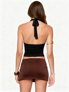 Detail of black halter tie top and low-waist brown mini skirt with an open back design