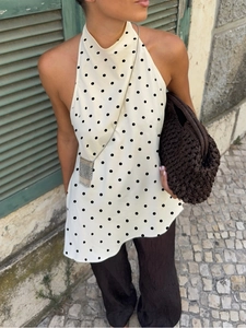 Polka dot sleeveless halter neck top with loose wide-leg trousers and woven clutch