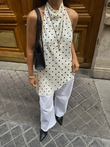 Detail view of polka dot halter top with pleated neckline and irregular asymmetrical hem