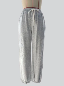 Detail of grey joggers featuring white star patches, ribbed cuffs, and drawstring waist