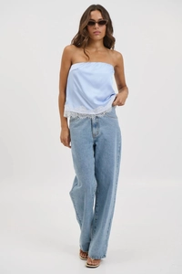 Detail of light blue satin tube top with delicate white lace trim and denim jeans