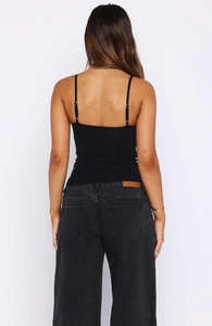 Back view of a black slim fit V-neck crop top with adjustable spaghetti straps on a model