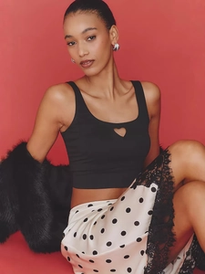 Slim fit black heart cutout camisole top paired with a polka dot lace skirt on red background