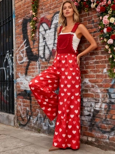 Detail eines roten Jumpsuits mit Herzprint und Volantstufen vor Rosen-Hintergrund