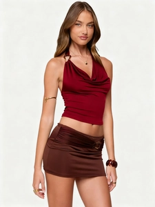 Detailed view of deep red halter top with V-neck pleats and metal buckle accents