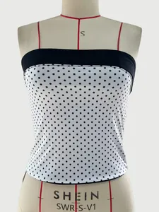 Detailed close-up of white tube top with black polka dots and slim red shoulder straps