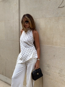Detail of white polka dot halter top featuring an irregular hem and side slit design