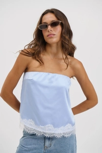 Detail of light blue satin bandeau top with elegant white lace hem and glossy finish