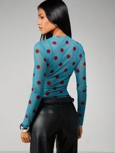 Detail of sheer blue mesh long sleeve top with bold red polka dots on female model