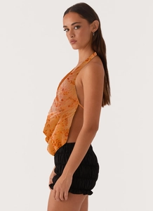 Détail du haut licou orange à paillettes brodées et du short noir à taille froncée