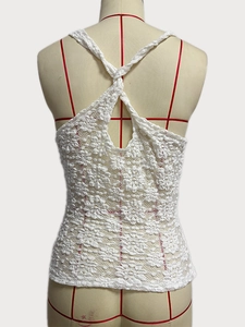 Détail du haut en crochet blanc montrant le design avec des lacets croisés au dos