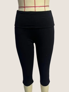 Detail of high-waist black capri yoga leggings featuring elastic knitted fabric texture
