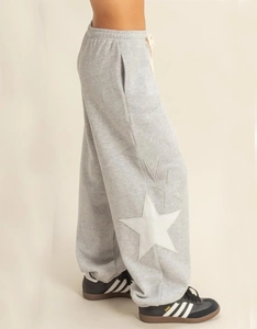 Detail of grey jogger pants with white star patches and drawstring waist
