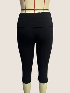 Detail view of the wide elastic waistband on black high-waisted capri leggings