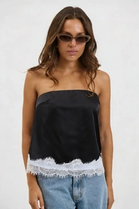 Detail of black satin tube top with delicate white eyelash lace trim and denim jeans