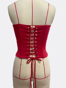 Detailed back view of red lace-up corset top with silver eyelets on a mannequin