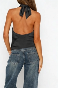 Macro view of black satin halter top featuring an open back and silk texture