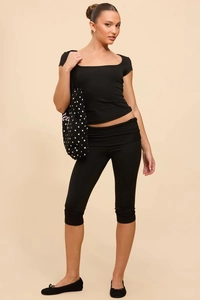 Detail view of black square neck short sleeve top and matching cropped leggings on model
