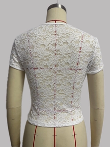 Close-up of white floral lace texture and refined hem stitching on the summer top