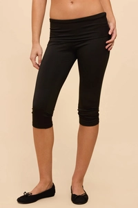 Detail of high-waist black cropped leggings with elastic fabric and calf-length cut