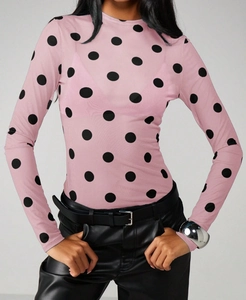 Close-up of pink sheer mesh top with bold black polka dots and fitted crew neck design