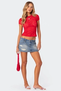 Detail of red floral lace crop top and distressed light blue denim mini skirt on model