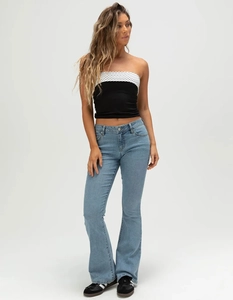 Fashionable polka dot tube top paired with light blue flare jeans on a studio model