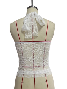 Back view of a white floral lace halter top with detailed neck ribbons and sheer texture