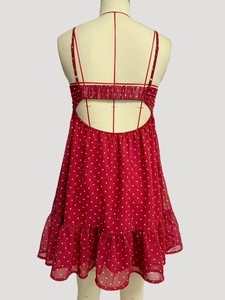 Back view of red polka dot mini dress featuring backless design and ruffled hem detail