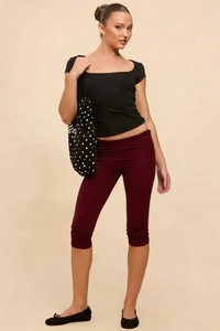 Detail view of burgundy cropped leggings featuring a stylish high-waisted fold-over waistband