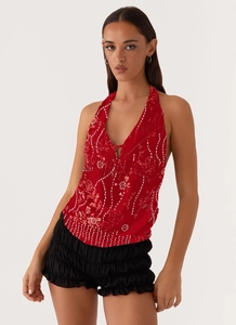Détail du haut dos nu rouge avec appliqués floraux pailletés et design sans dos élégant