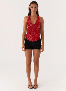 Détail du haut dos nu rouge à paillettes et du short noir à volants superposés