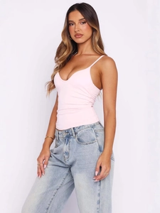 Pink V-neck sleeveless crop top with ruching and denim jeans on a studio model