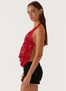 Détail du haut dos nu à paillettes rouges avec fleurs et short noir texturé