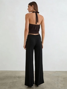 Rear view of woman in dark brown halter neck top and black high-waisted wide-leg trousers