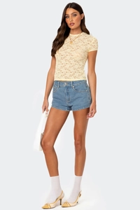 Close-up of a pale yellow lace short-sleeve top with delicate floral crochet patterns