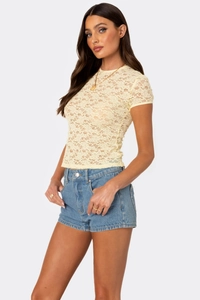 Close-up detail of pale yellow floral lace fabric and delicate texture on short sleeve top
